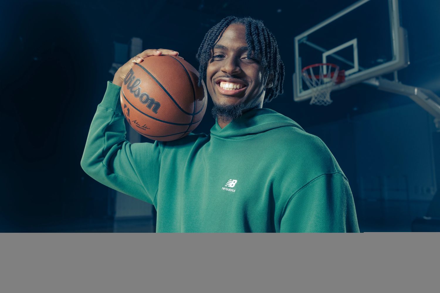 Tyrese Maxey models a green New Balance hoodie.